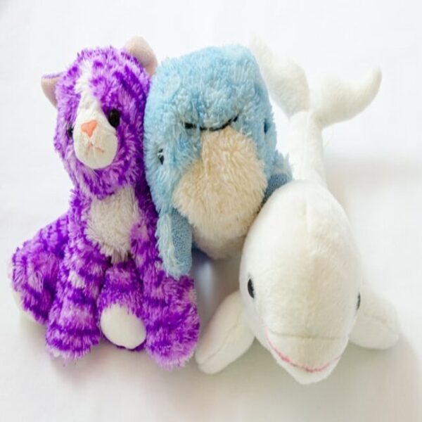 Three stuffed animals - fuschia and white kitten, blue and cream whale, white dolphin. They look soft and cute.